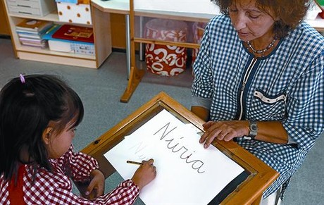 El 'pupitre màgic' La Maria Àngels ensenya a escriure el seu nom a una alumna a la taula de vidre.